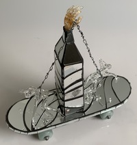 <div class='title'>Push Me Pull You</div><br>Flameworked figures, kiln-cast wheels, sheet glass, mirror, skateboard, borrle, artist-wrought chain, copper foil and solder <br>17.5"w x 17"h x 7"d<br>