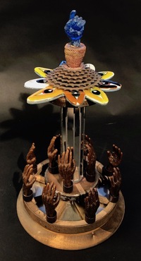 <div class='title'>Prophesy</div><br>fused and cast glass, wax cast hands, mirror, vintage wagon wheel, vintage wooden spool, bike free wheel, brass findings<br>20.5"h x 11"d<br>