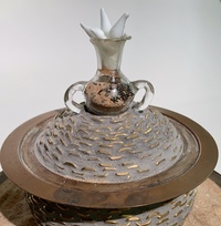 <div class='title'>Seed Safe</div><br>Flameworked points and vessel, vintage wagon wheel, silver server, mirror, fescue, sand, found glass dome, brass chain <br><a href='videos/657.mov' target=_blank>VIDEO!</a><br>11.5"h x 14"w x 14"d<br>