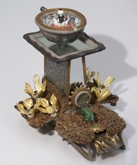 <div class='title'>Point the Way</div><br>Cast glass hand, flameworked/guilded flowers, flameworked eye and points, vintage toaster, vintage ice skates, silver chalice, mirror, vintage bundt pan, moss, found objects <br><a href='videos/658.mov' target=_blank>VIDEO!</a><br>14"h x 13"w x 14.5"d<br>